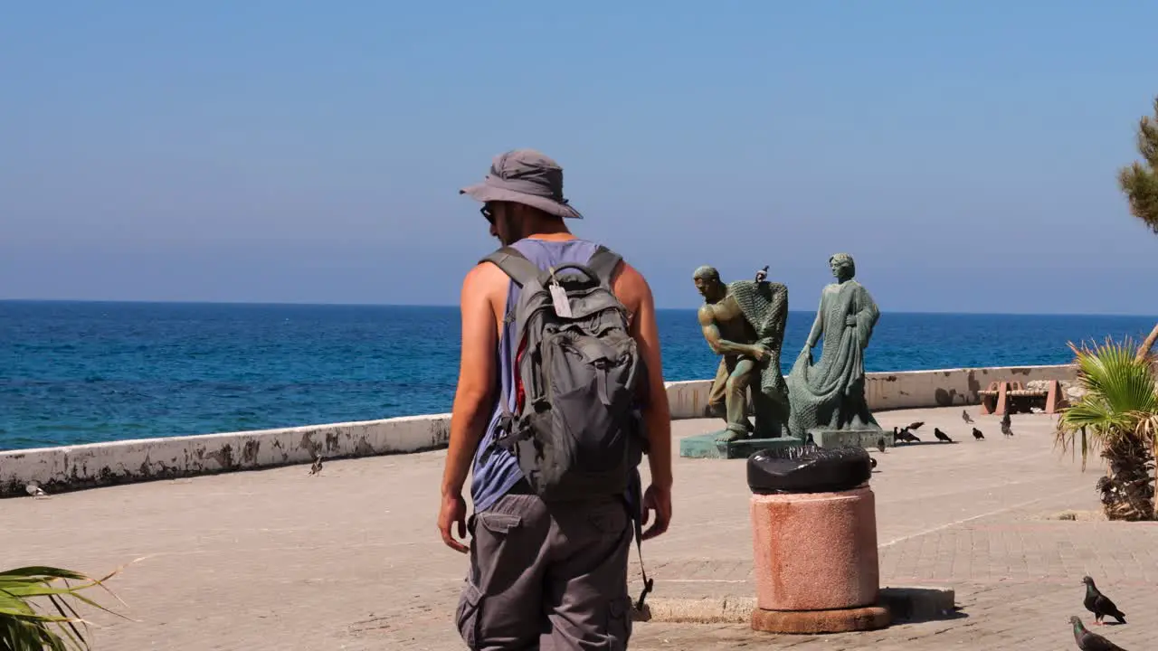 Male Tourist With Backpack Walking Along Promenade In Nicosia