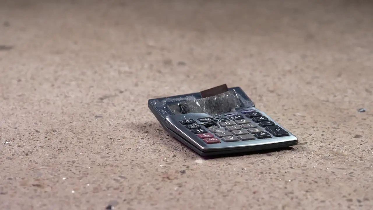 Hammer smashing already broken calculator on stone floor Slow Motion Closeup