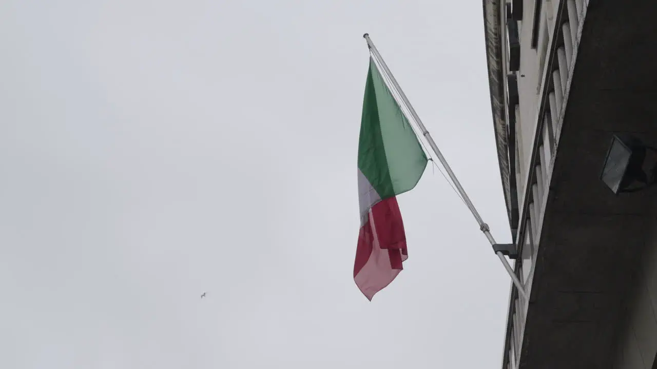 National flag of Italy waving while hanging on building facade slow motion shot