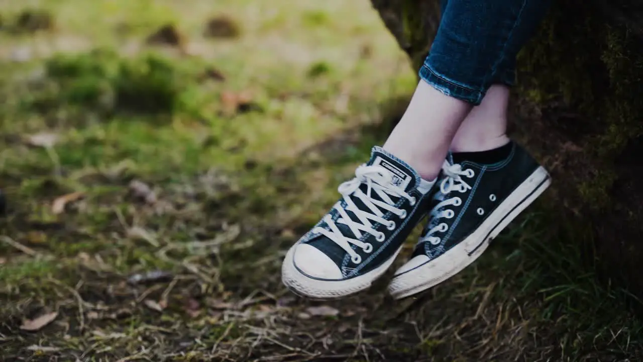 Girl swings feet wearing canvas sneakers slow motion