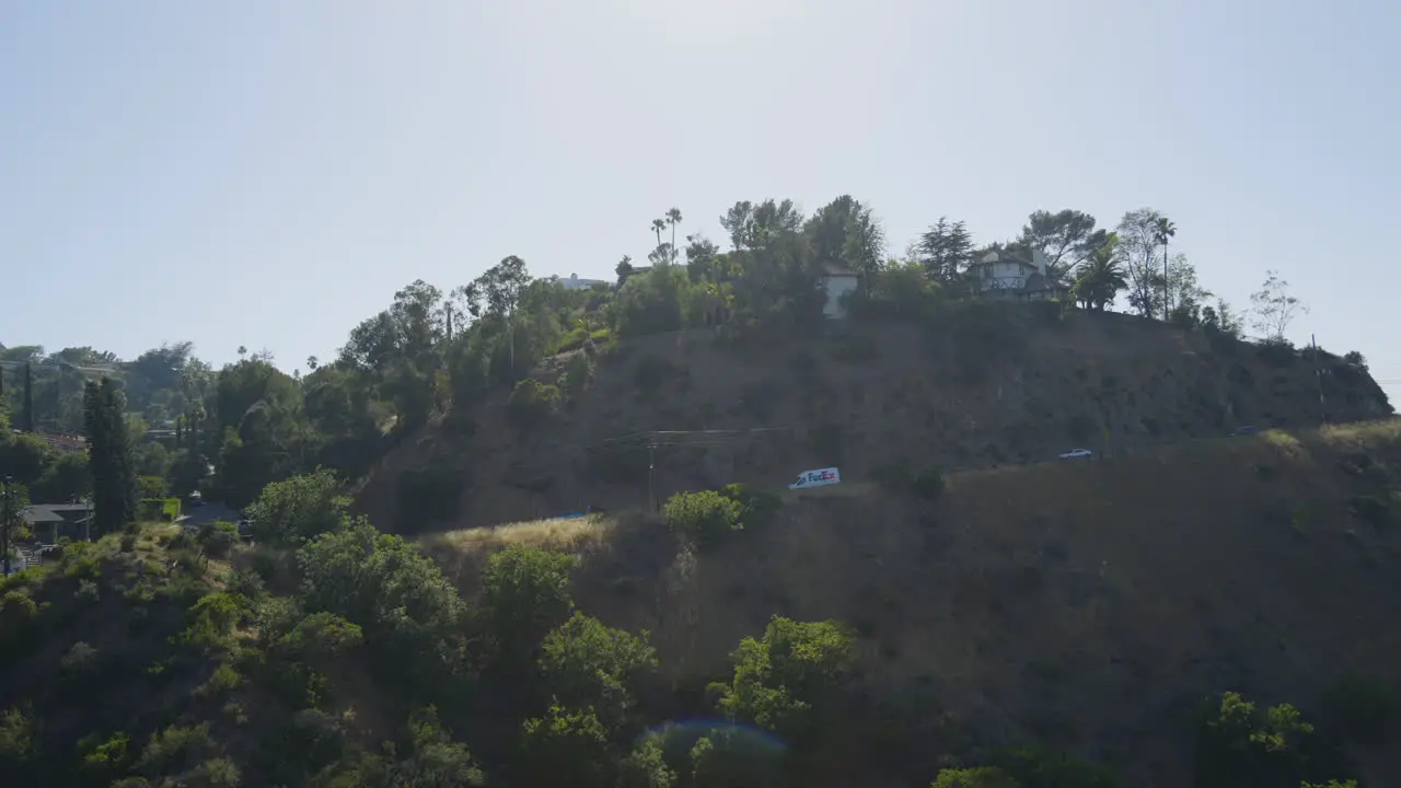 Tracking shot of delivery truck driving down windy mountain road located in the Hollywood Hills Southern California