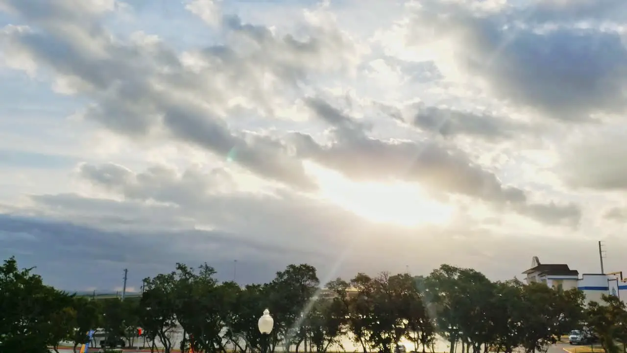 Time lapse of Storm clouds clearing to reveal blue skies and sunrays over trees