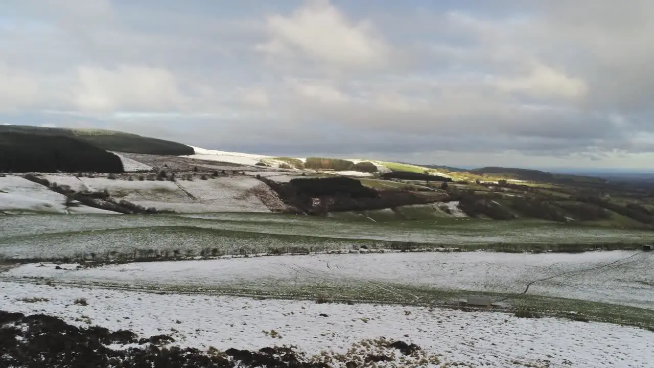 Snowy rural winter valley countryside aerial agricultural farmland landscape pan slow right