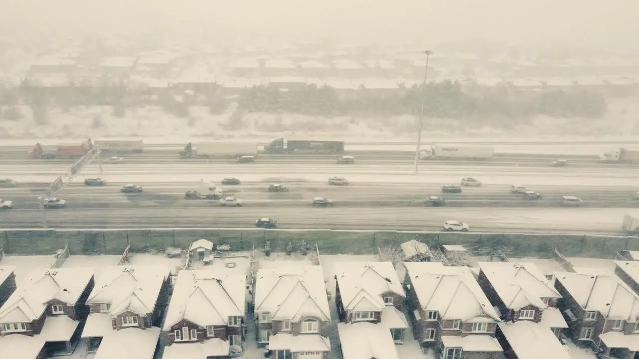 Aerial over busy highway snowstorm middle class houses