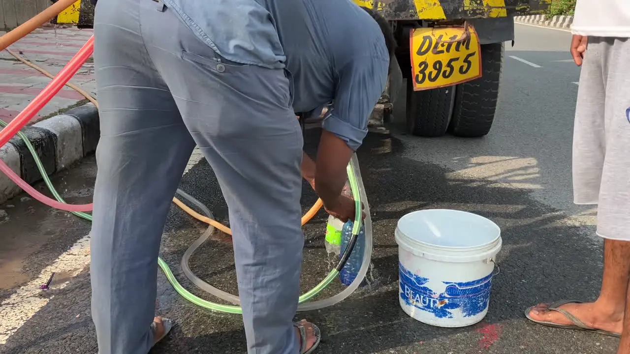 A taxi driver fills water bottles from a Government water tanker