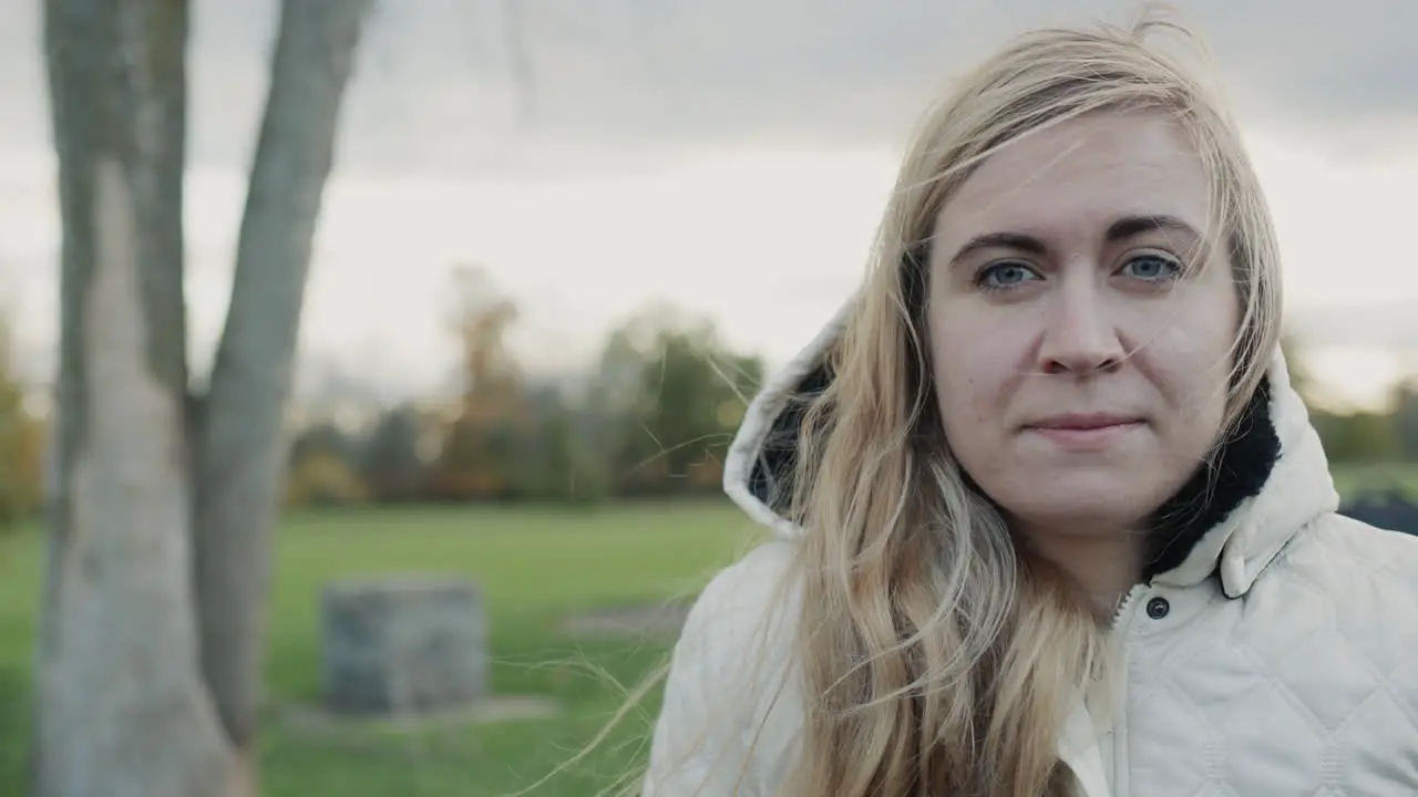 Portrait of a young pensive woman in an autumn park Standing in a jacket with a hood on her head