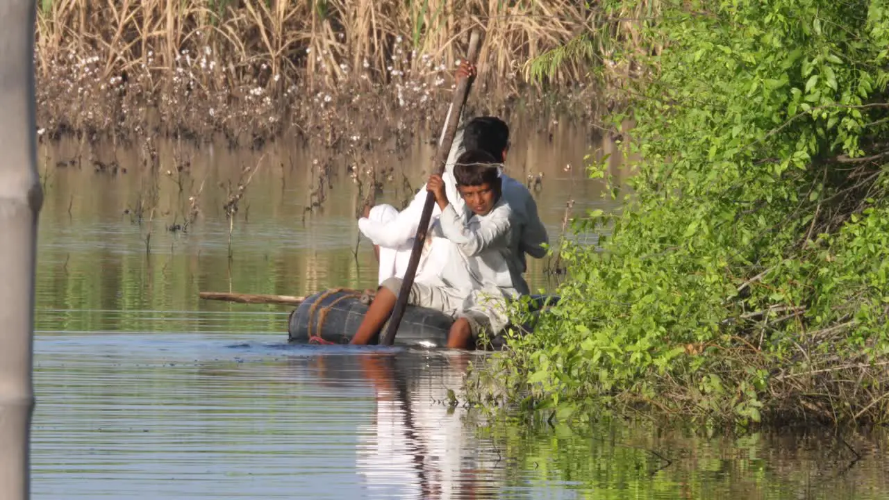 Child Floating On Large Rubber Tyre On Flooded Land Using Stick To Manoeuvre In Sindh Pakistan