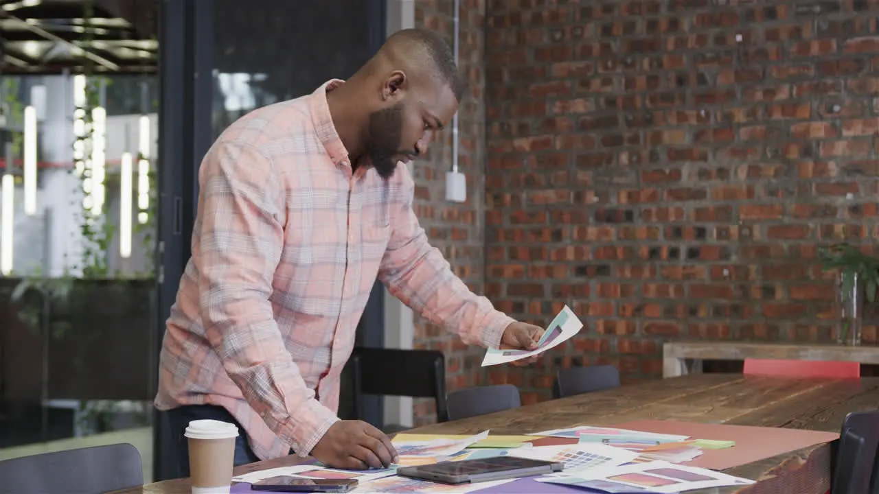 African american male creative looking at designs in office slow motion