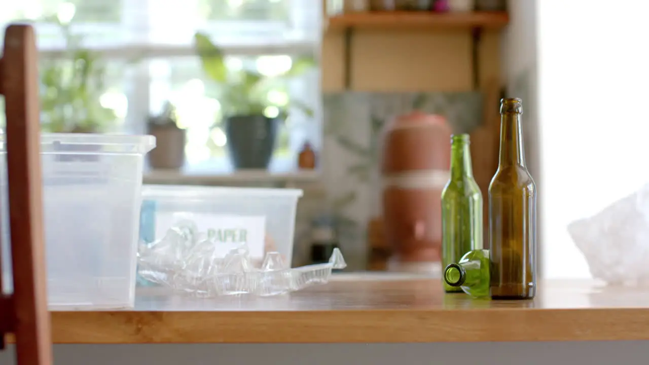 Segregation plastic boxes for waste plastic and glass bottles on table in kitchen slow motion