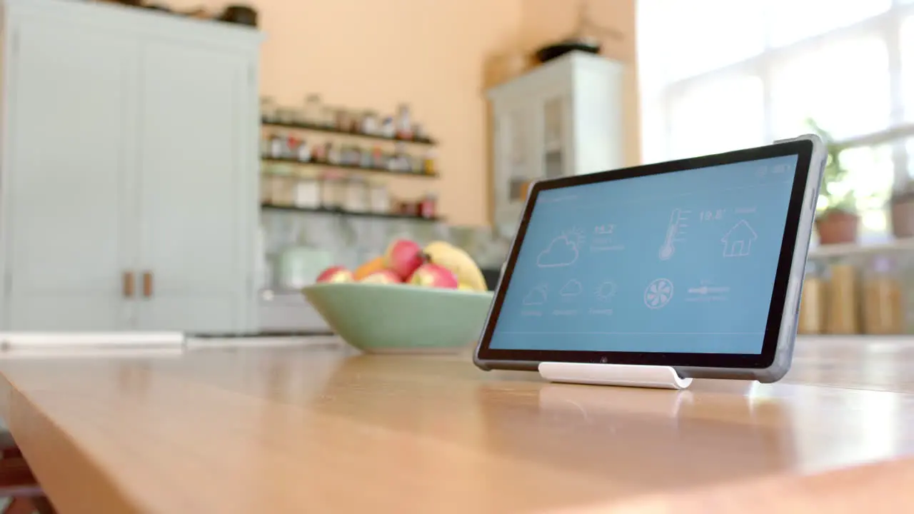 Close up of tablet with smart home on screen over fruit in bowl in kitchen slow motion