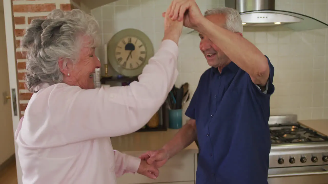 Senior caucasian couple dancing in kitchen in slow motion