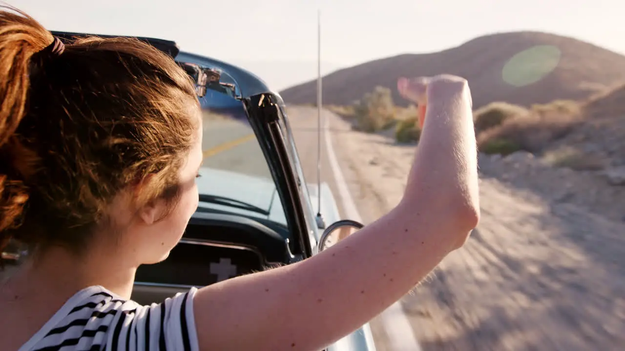 Woman in the front passenger seat of open top car back view