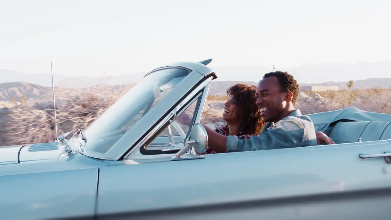 Smiling black couple driving on a desert highway close up