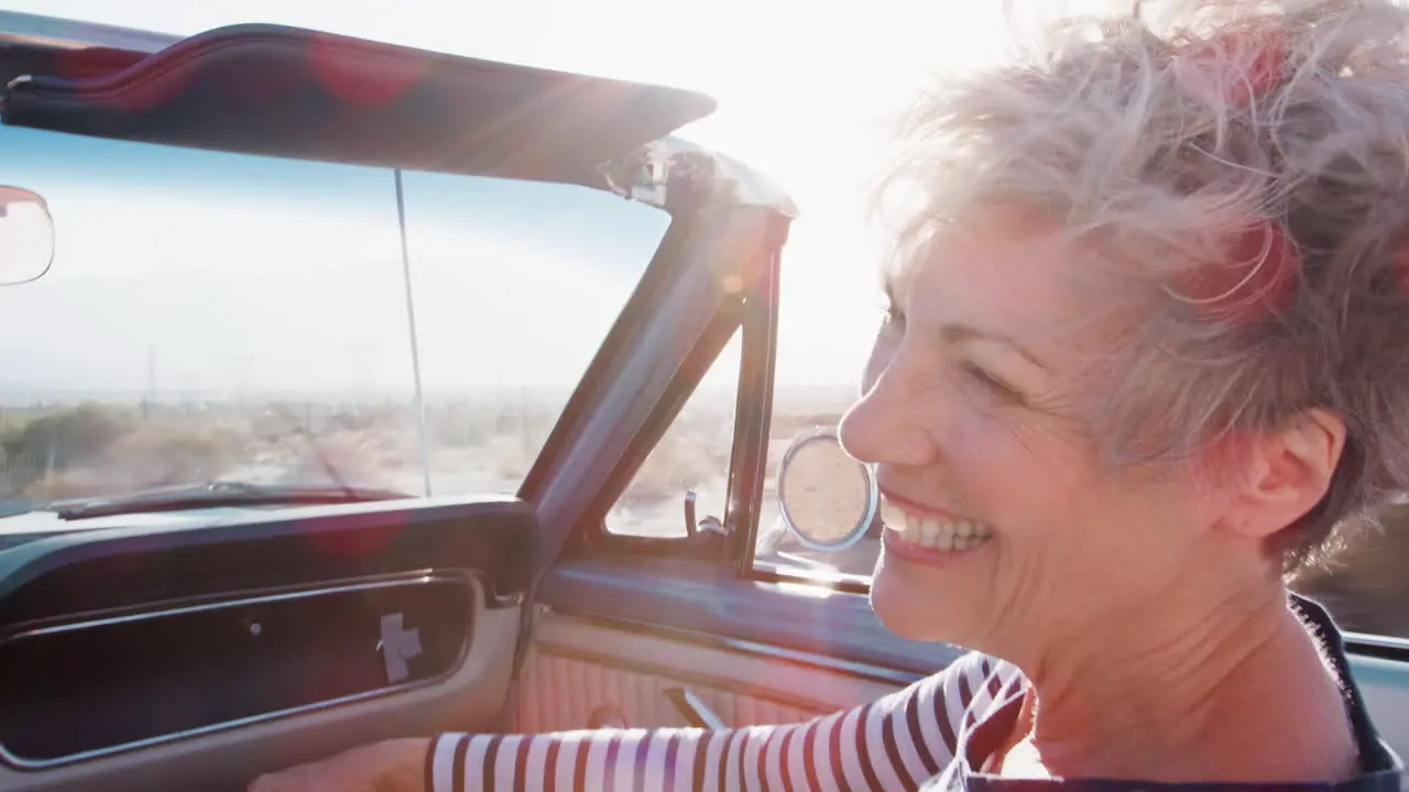 Happy senior female passenger in a convertible car close up