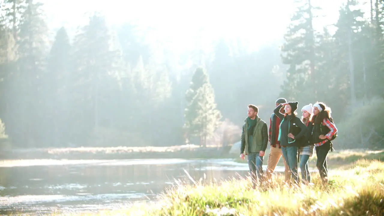 A group of friends hiking near lake stop to admire the view