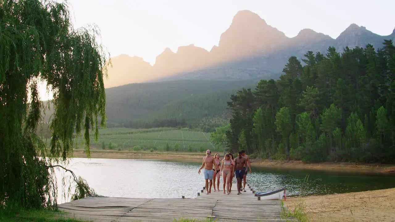 Group of young adult friends walking on a jetty to camera