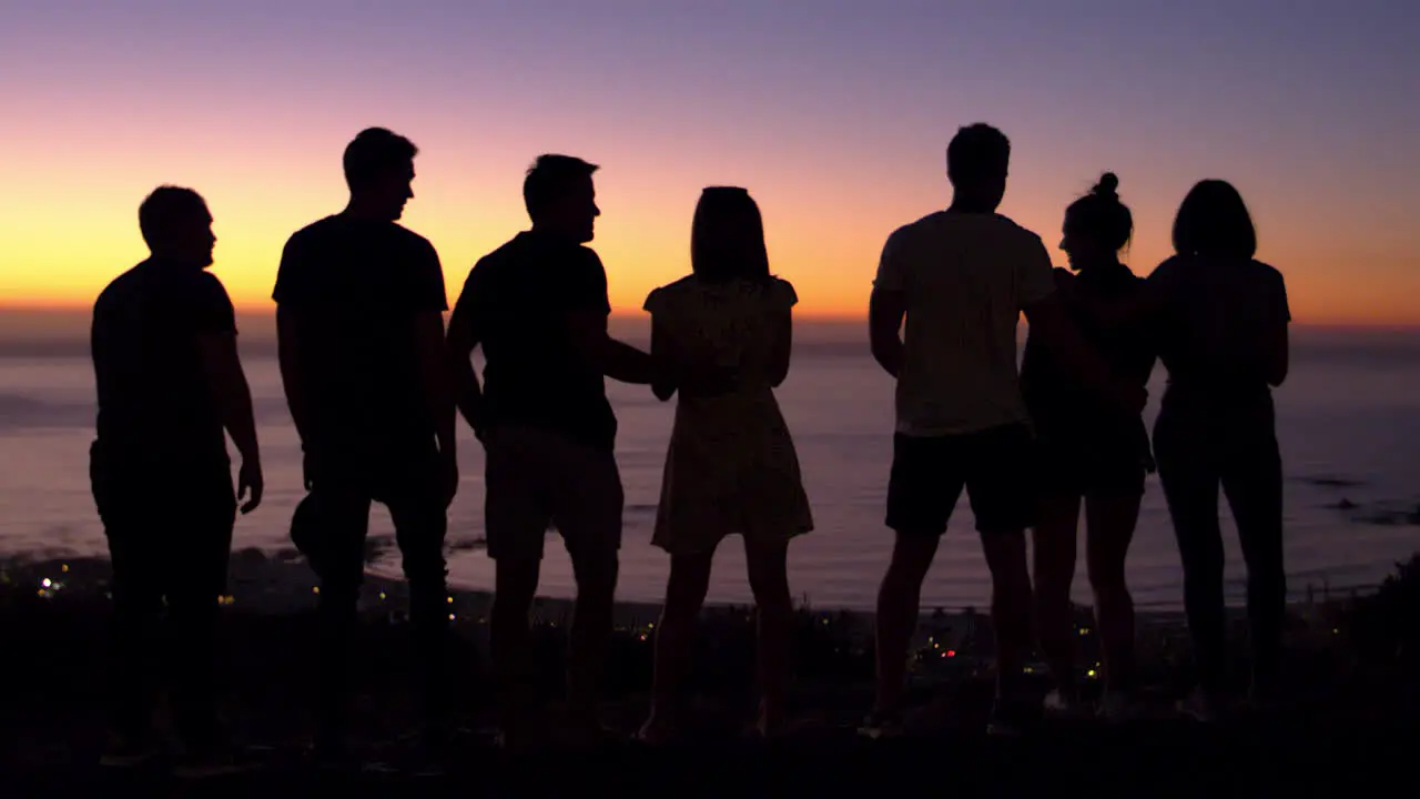 Group of young adults talking at sunset on a beach