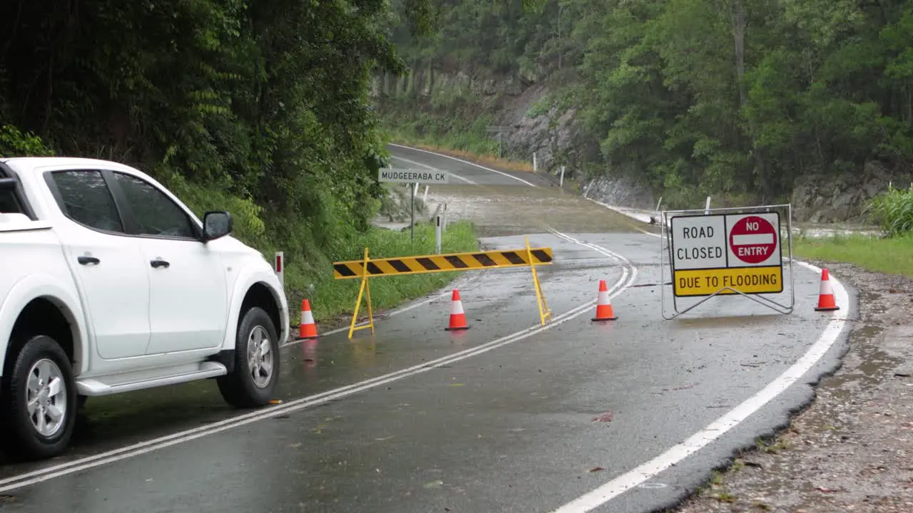 Mudgeeraba Gold Coast 02 January 2024 White car waits at road closure due to flooding across Mudgeeraba Creek Bridge causing road closure