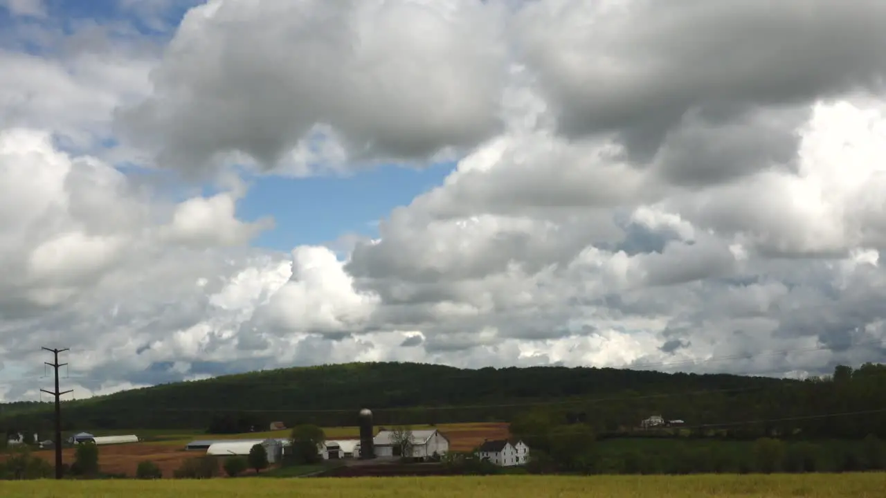 A farm in the valley and clouds passing overhead in the springtime