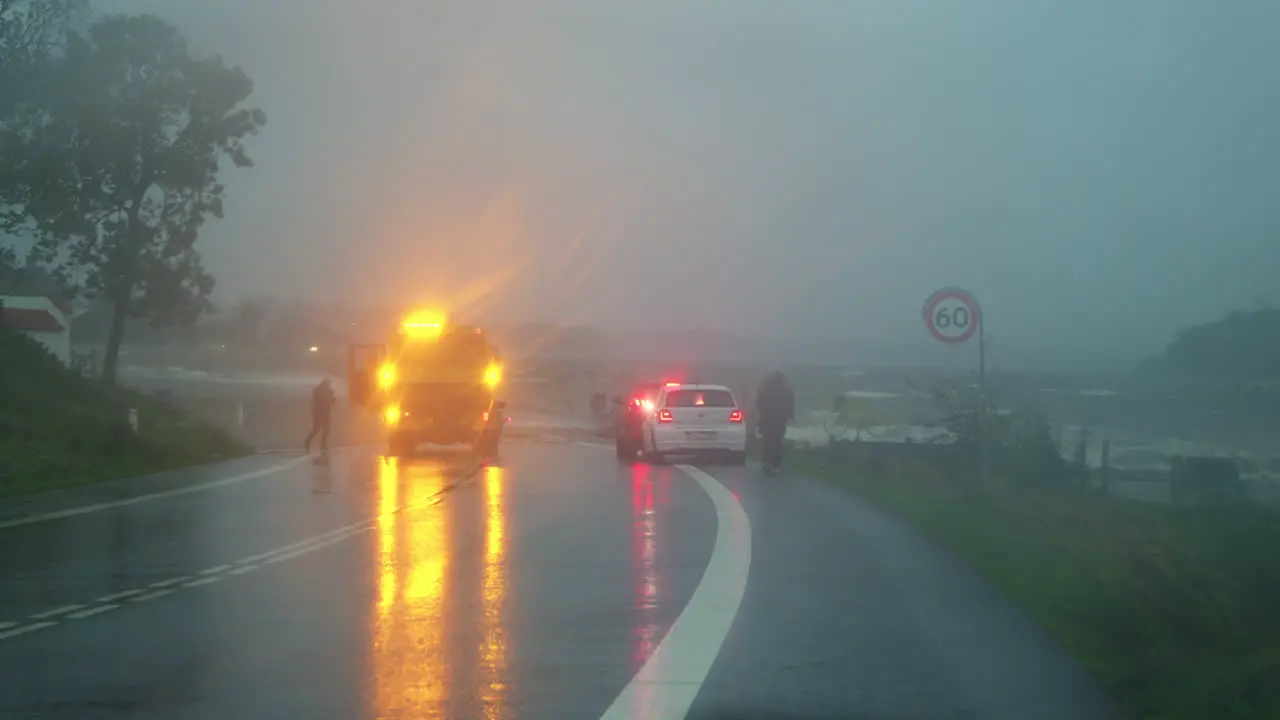 Emergency response to storm surge in Kollund with vehicles and personnel on a rainy road