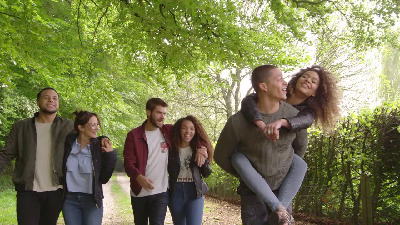 Young adults walking and piggybacking in a country lane shot on R3D