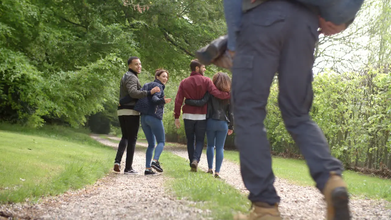 Young couples walk and piggyback in country lane back view