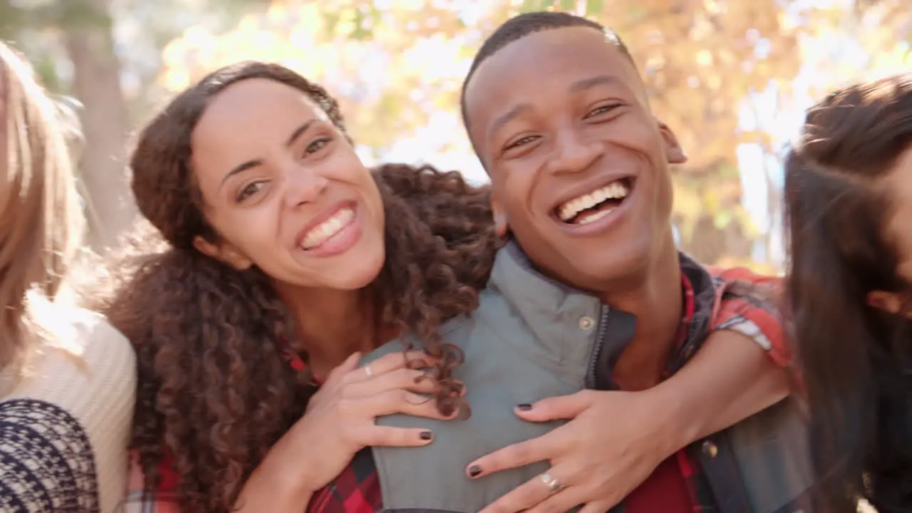 Close up handheld pan of three couples piggybacking outdoors