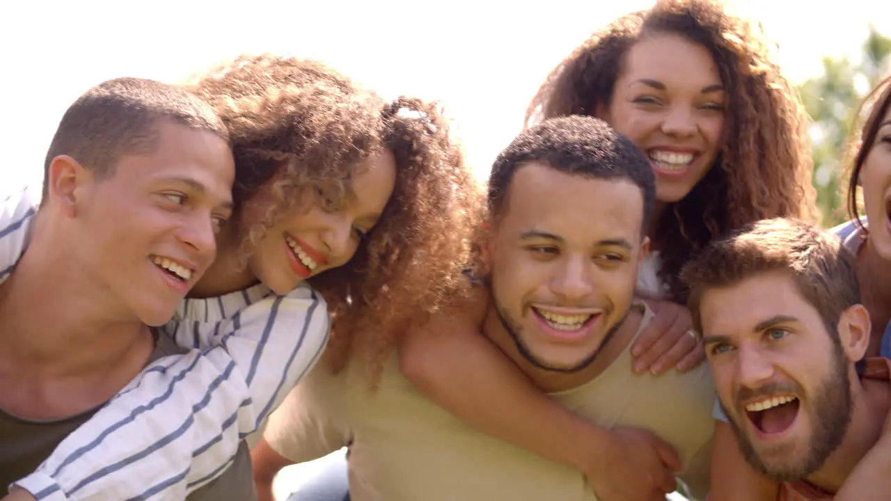 Close up of six young adult friends piggybacking outdoors