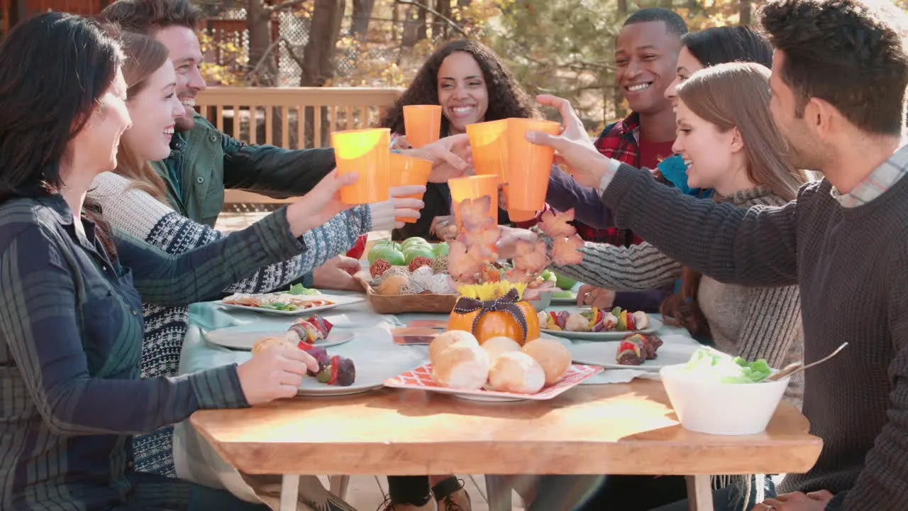 Group of happy friends at a table outdoors making a toast