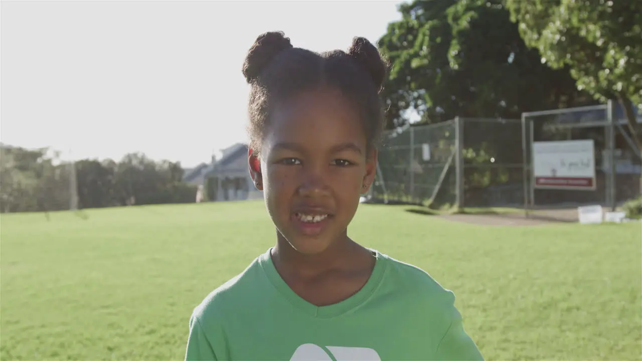 Biracial girl smiles brightly outdoors wearing a green recycling t-shirt with copy space