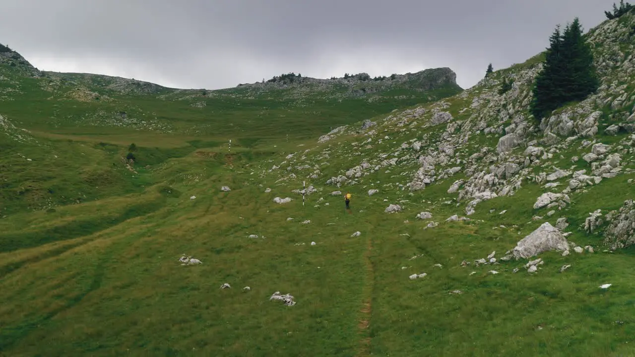 Pan wide angle shot revealing a hiker crossing a mountain alpine valley