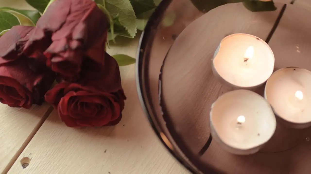 Floating tea lights and bouquet of red roses background