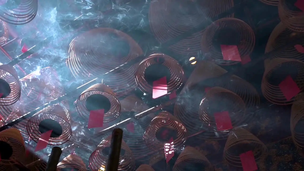 Slow-motion footage of incense coils hanging from the ceiling as they burn inside a Taoist temple to attract the attention of the gods in Hong Kong