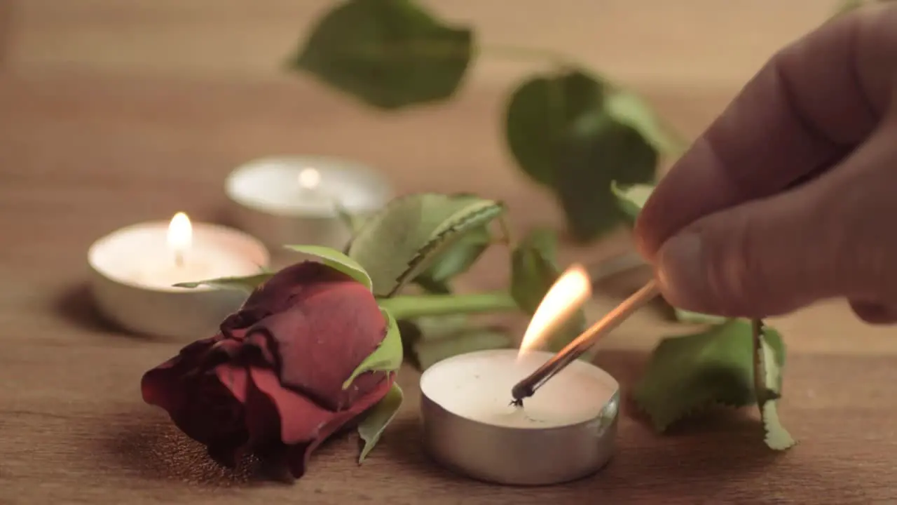 Lighting a tea light candle with red rose for romantic evening