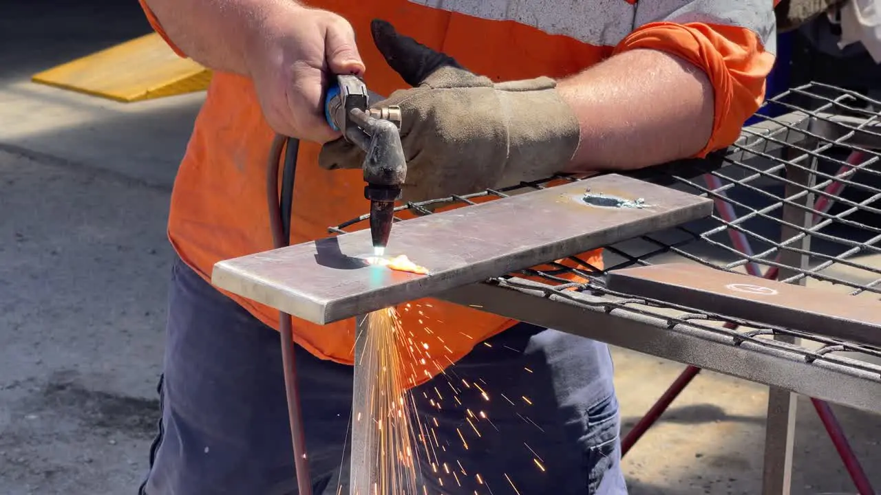 Gas welder being used to blow a hole into a sheet of steel