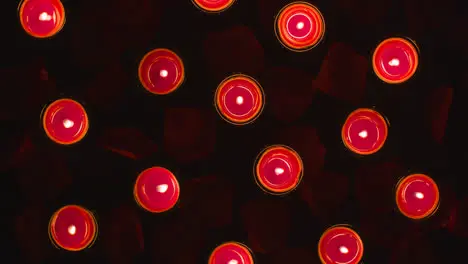 Overhead Shot Of Romantic Lit Red Candles On Background Covered In Rose Petals