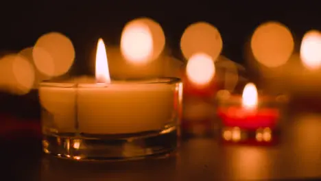 Close Up Of Romantic Lit Red And White Candles Burning On Black Background With Bokeh Lighting