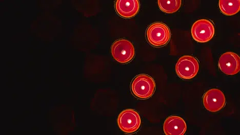 Overhead Shot Of Romantic Lit Red Candles On Background Covered In Rose Petals With Copy Space