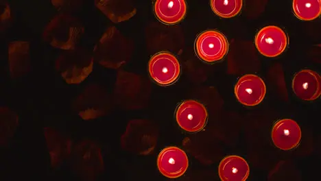 Overhead Shot Of Romantic Lit Red Candles On Background Covered In Rose Petals With Copy Space 1