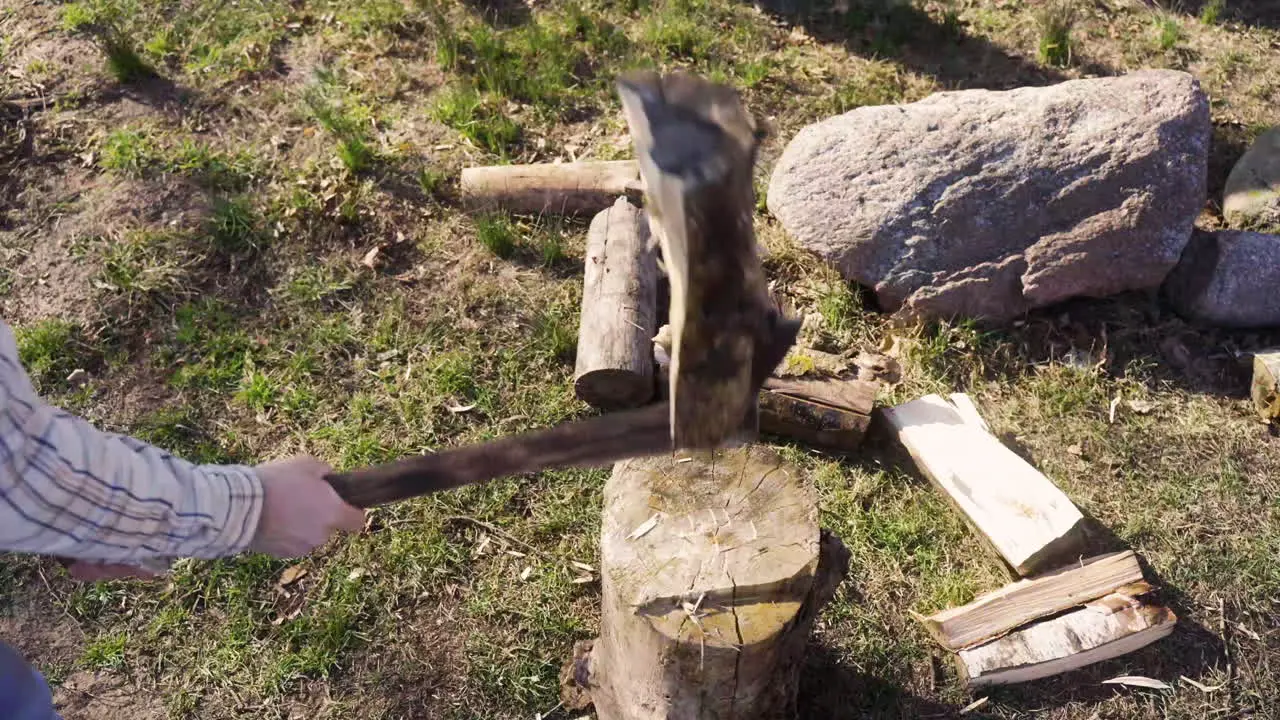 Top view of unrecognizable man chopping firewood with an ax outside a country house