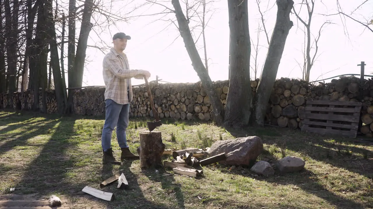 Caucasian man leaning on an ax resting after chopping wood outside a country house