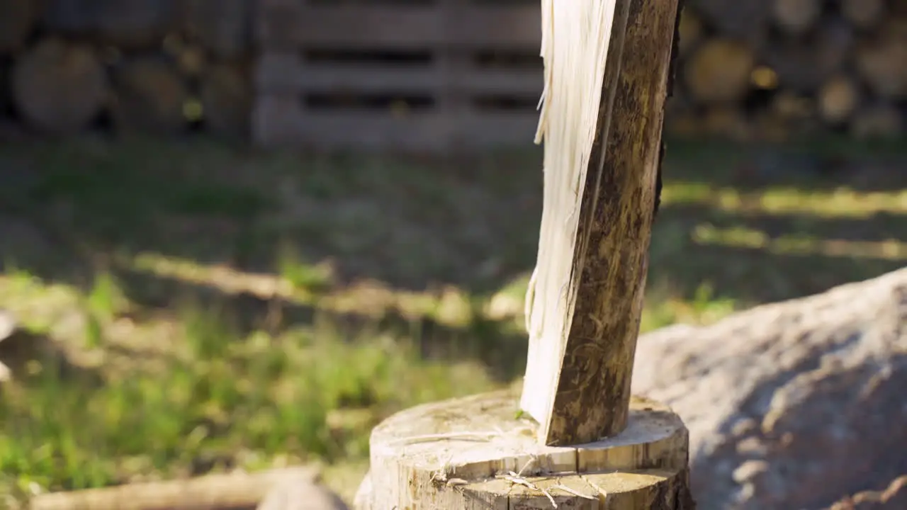 Close-up view of caucasian man chopping firewood with an ax outside a country house