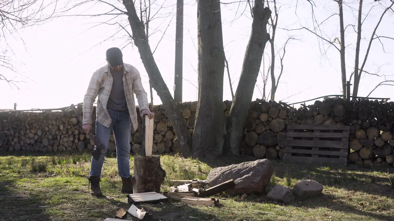 Caucasian man chopping firewood with an ax outside a country house