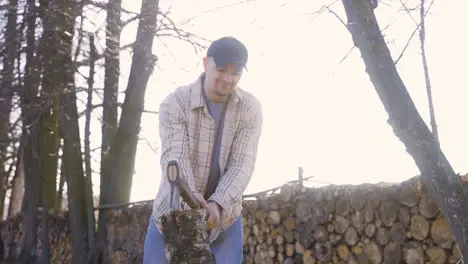 Caucasian chopping firewood with an ax in the countryside