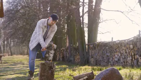 Caucasian chopping firewood with an ax outside a country house