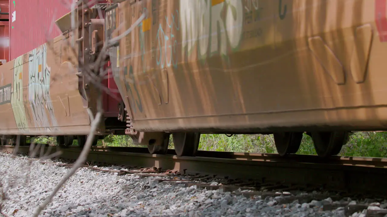 Low angle slow motion closeup of freight train cars passing by