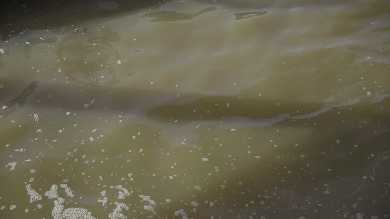 Muddy brown river water flowing in slow motion