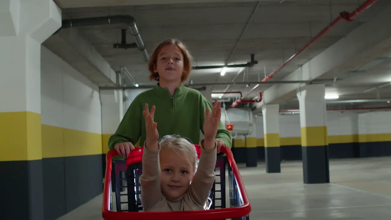 Brother pushes his sister in a shopping cart