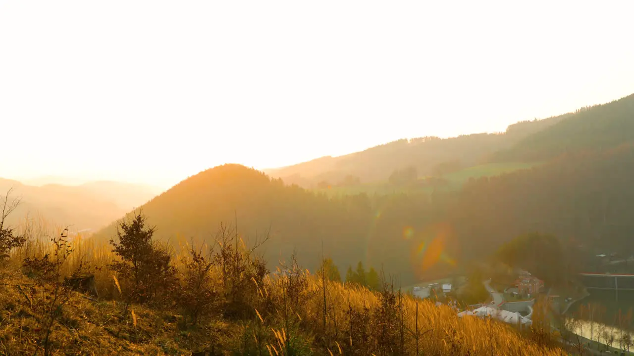 View of tall dry grass at the top of a hill that moves in strong wind to all sides captured during a sun match with a view of the surrounding nature and hills captured in 4k 60fps