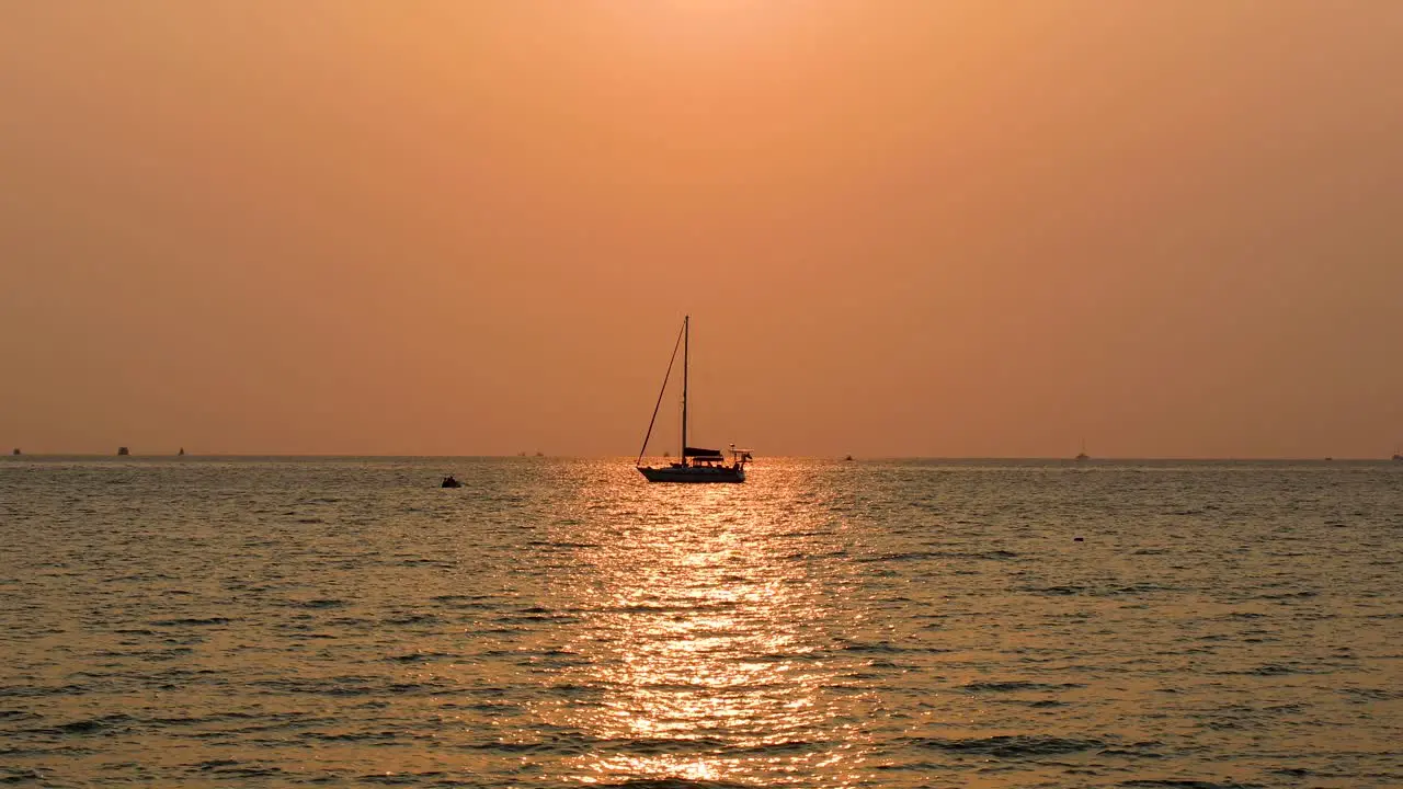 A Calm Sunset with a Yacht on the Horizon with Orange and Pink Skies Along the Ocean Horizon in Bangsaray near Pattaya Thailand